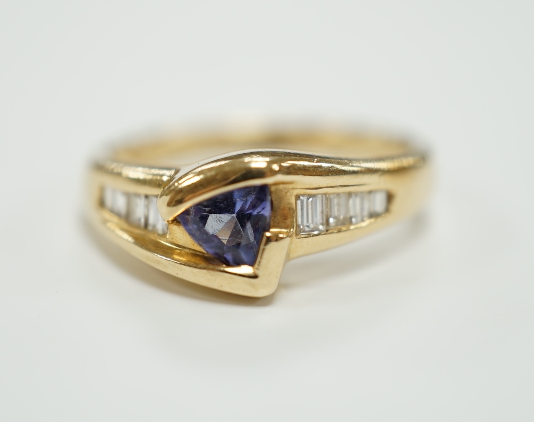 A modern 14ct and single stone tanzanite and graduated eight stone baguette cut diamond set ring, size K/L, gross weight 2.9 grams.